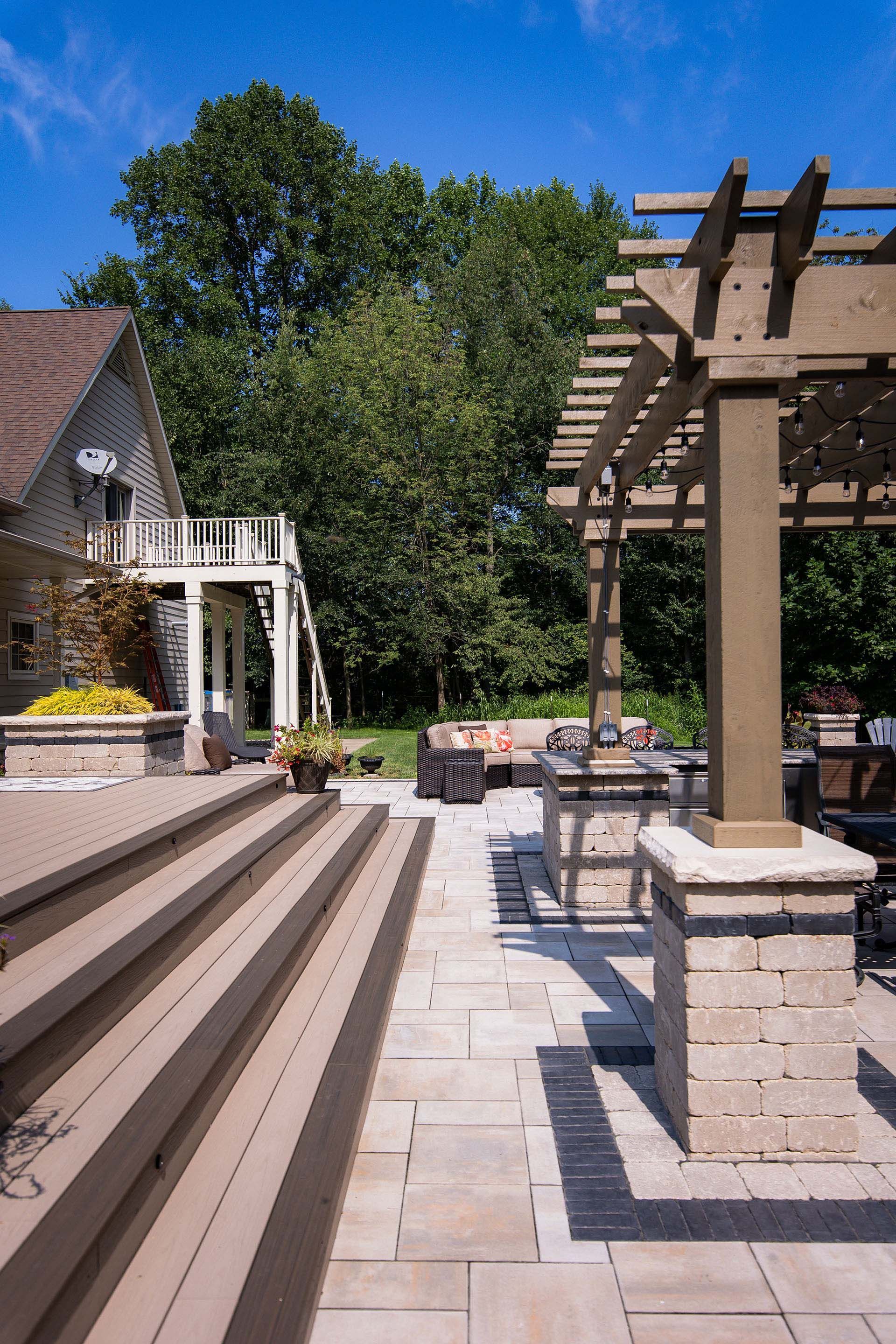 A patio with a pergola and stairs leading to a house.