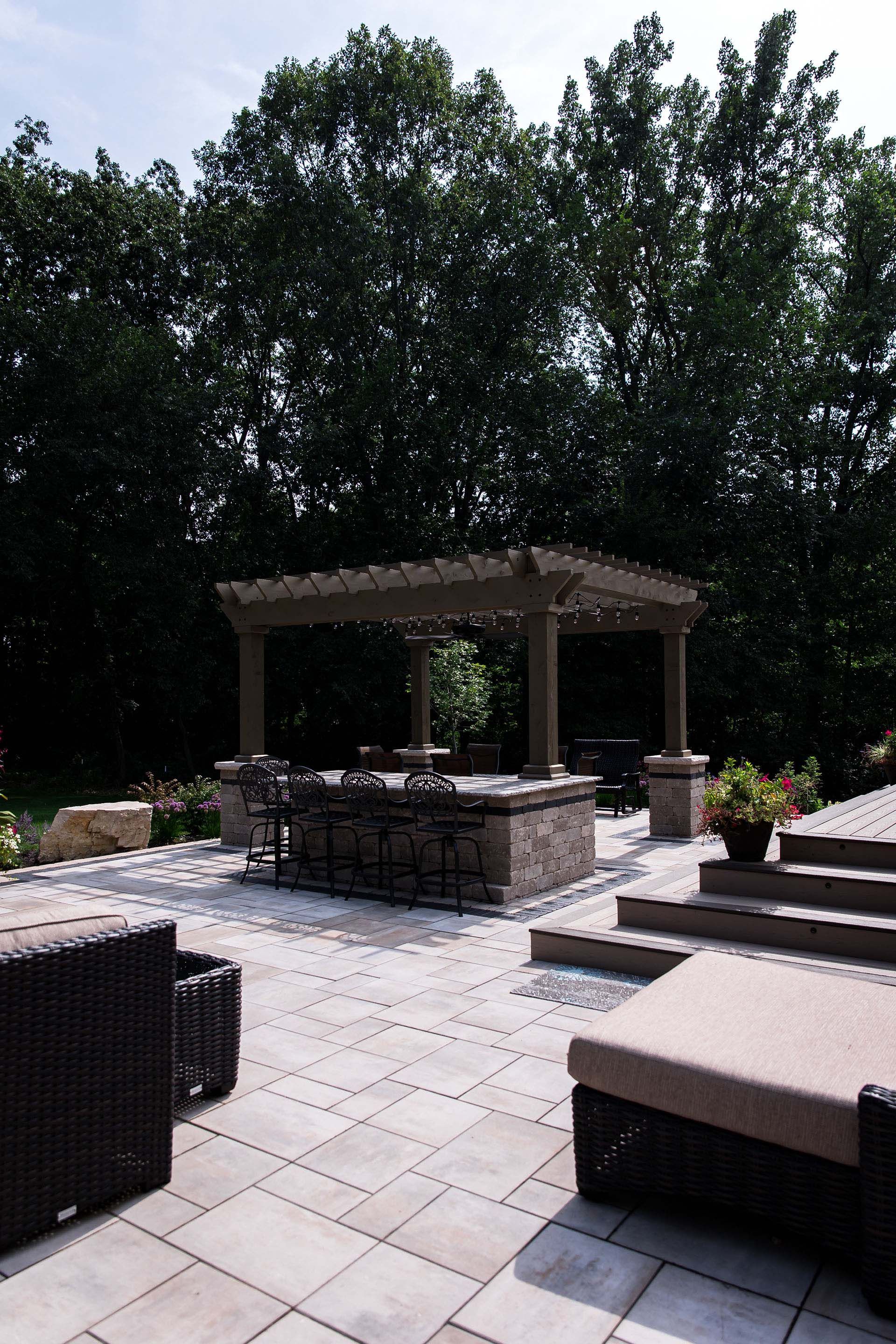 A patio with a pergola and a table and chairs