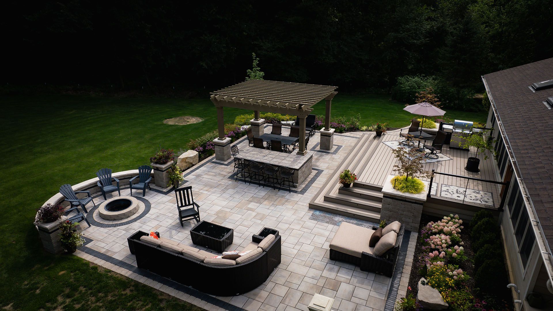 An aerial view of a large patio with a fire pit and a pergola.