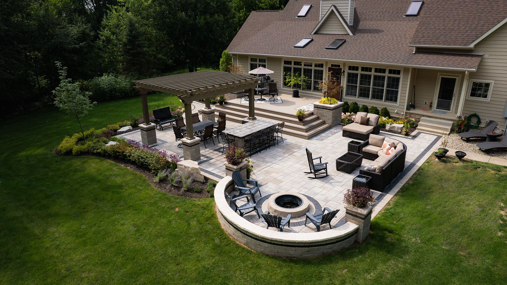 An aerial view of a large patio with a fire pit and a pergola.