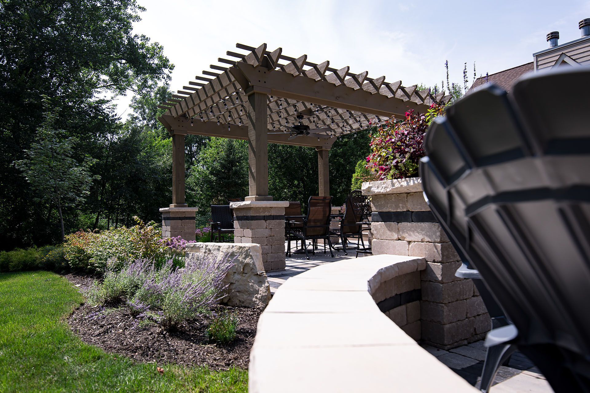 A patio with a pergola and chairs in the backyard