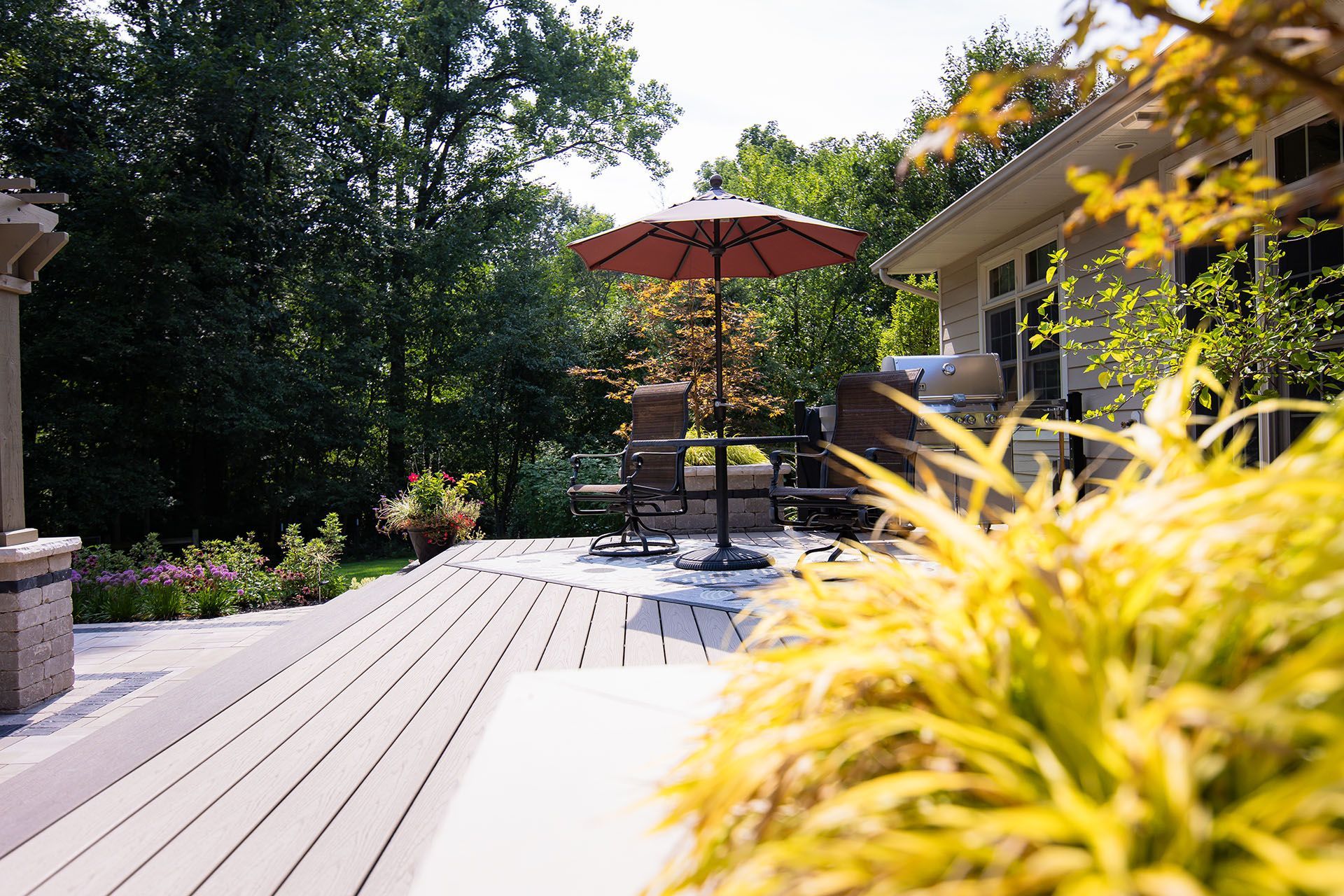 A deck with a red umbrella and chairs on it