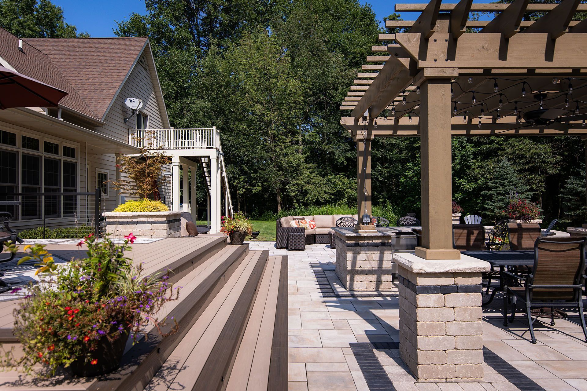 A patio with a pergola and stairs leading to a house