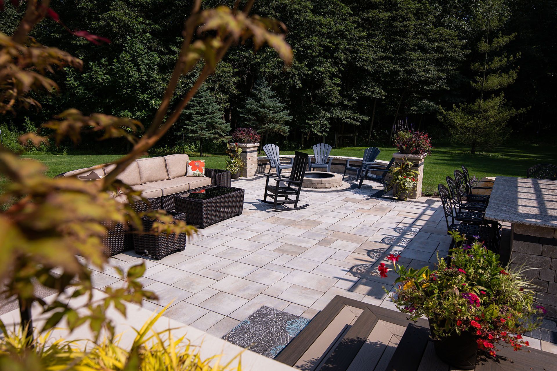 There is a patio with a fire pit and a lot of furniture on it.