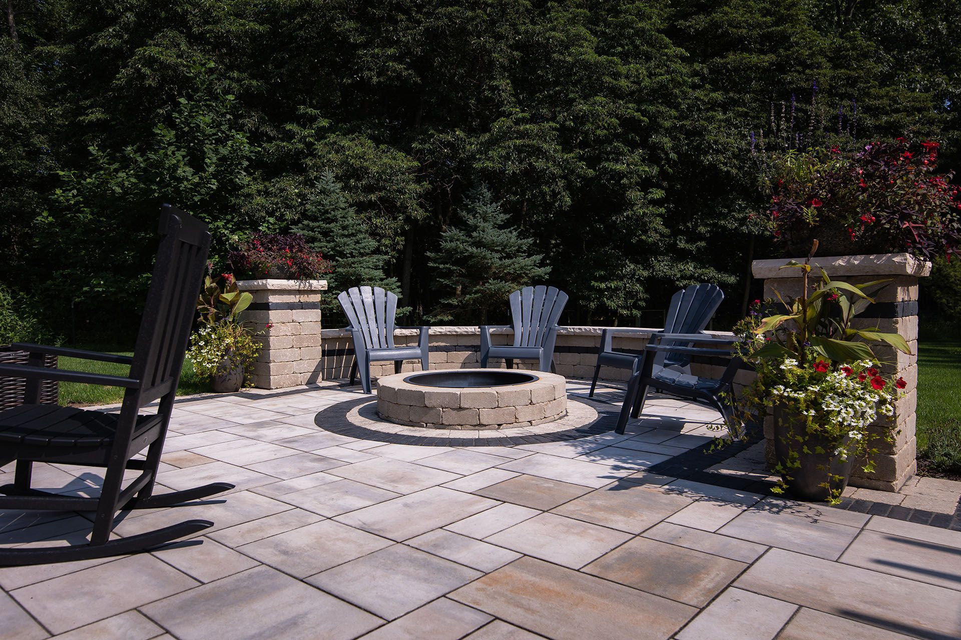 A patio with a fire pit and rocking chairs