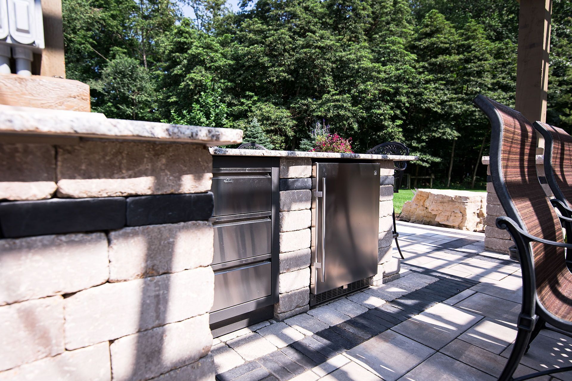 A patio with a stainless steel grill and a bench