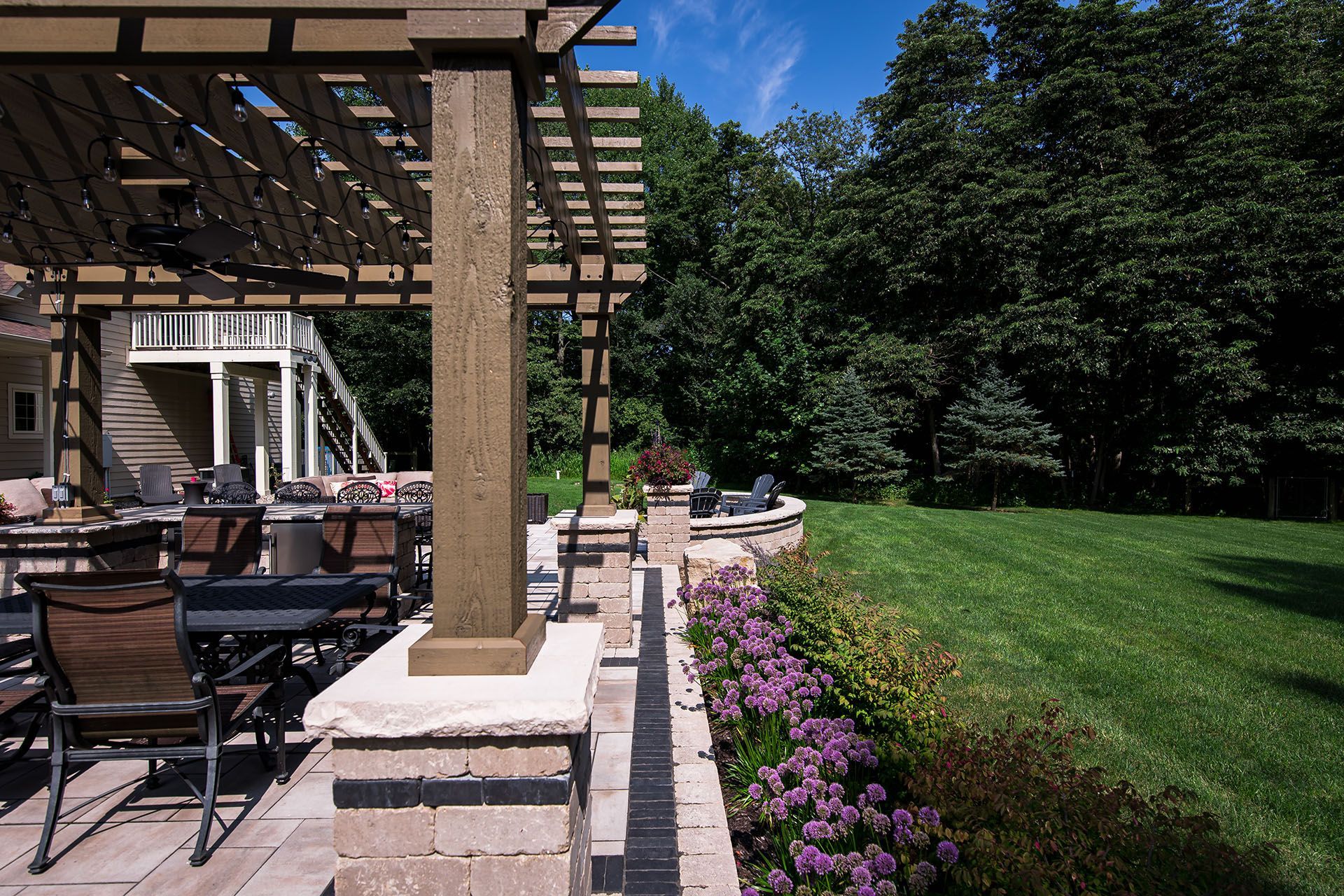 A patio with a pergola and purple flowers