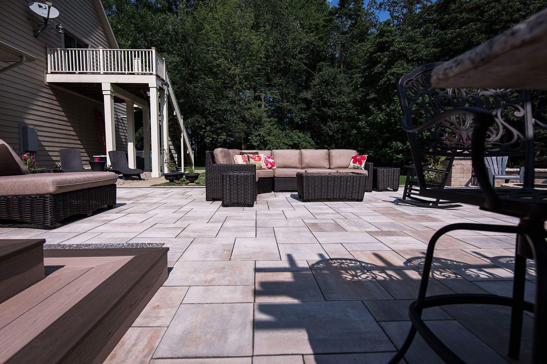 A patio with a couch , chairs and a table in front of a house.