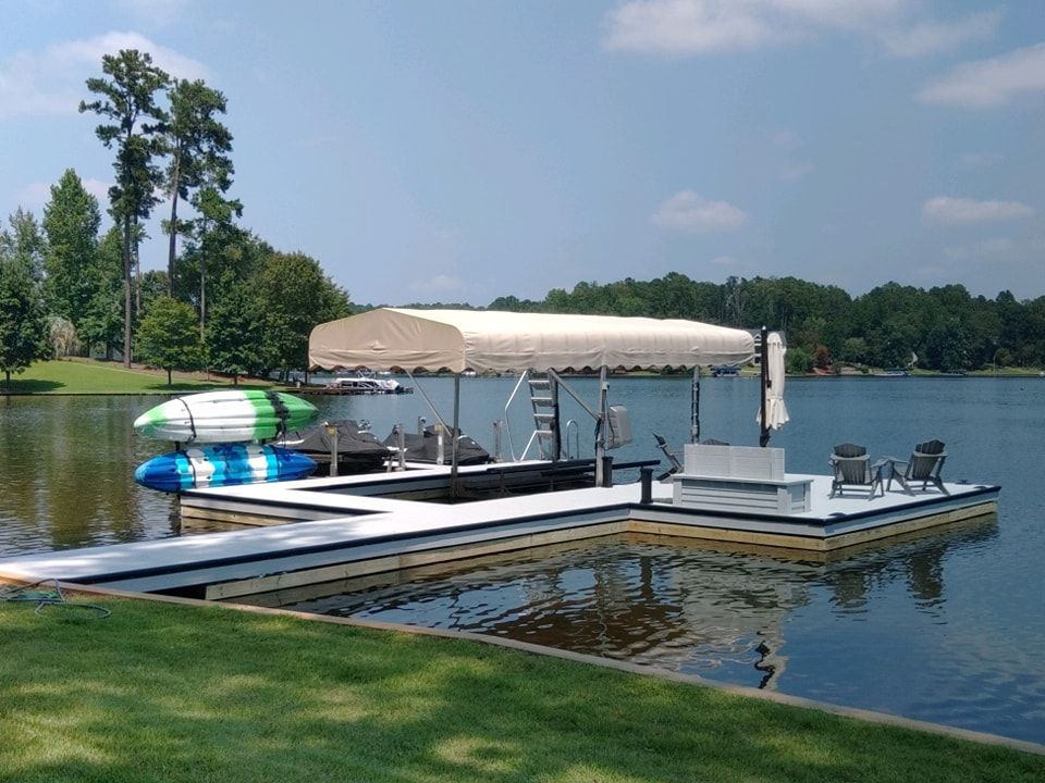 Lake dock with boat lift, kayaks, and seating under a canopy on a sunny day.