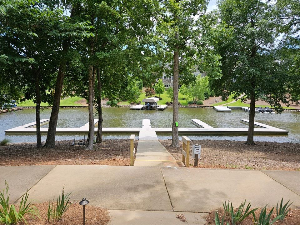 Pathway leads to a dock on a lake, surrounded by trees.