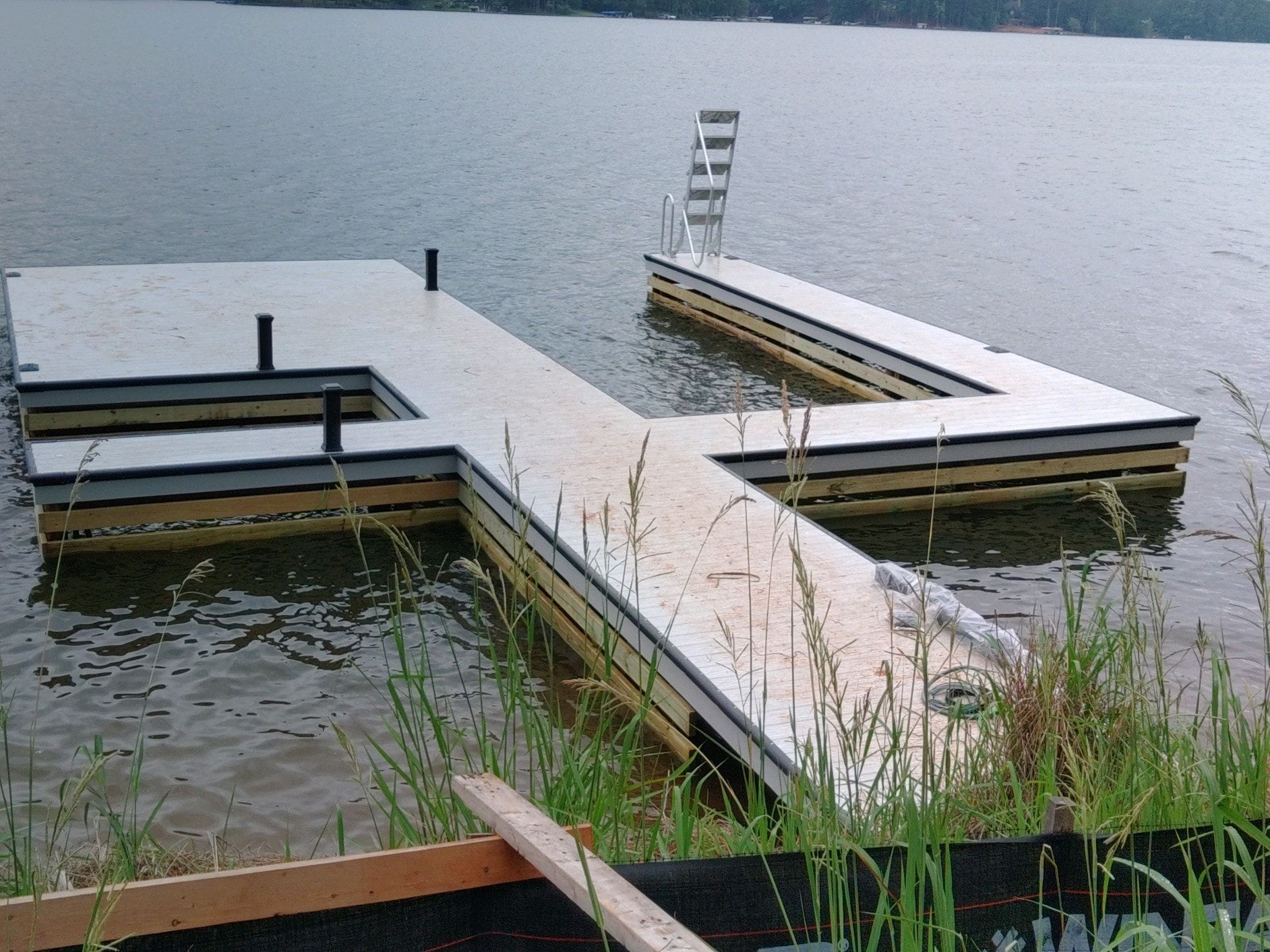 Wooden dock extending into water with a built-in ladder.
