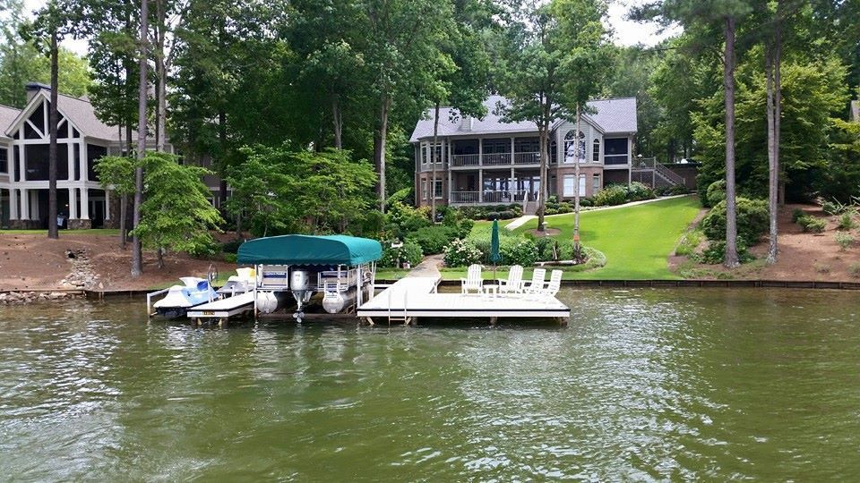 Lakefront homes with a dock, boats, and green trees.