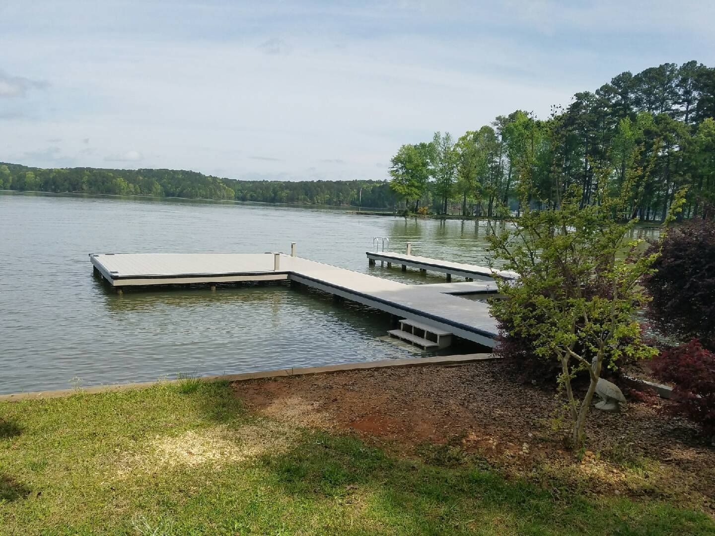 Lake with docks, green trees on the far shore, overcast sky.