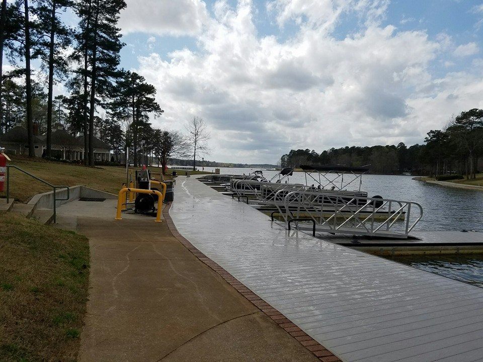View of a lake with docks, walkway, trees, and cloudy sky.