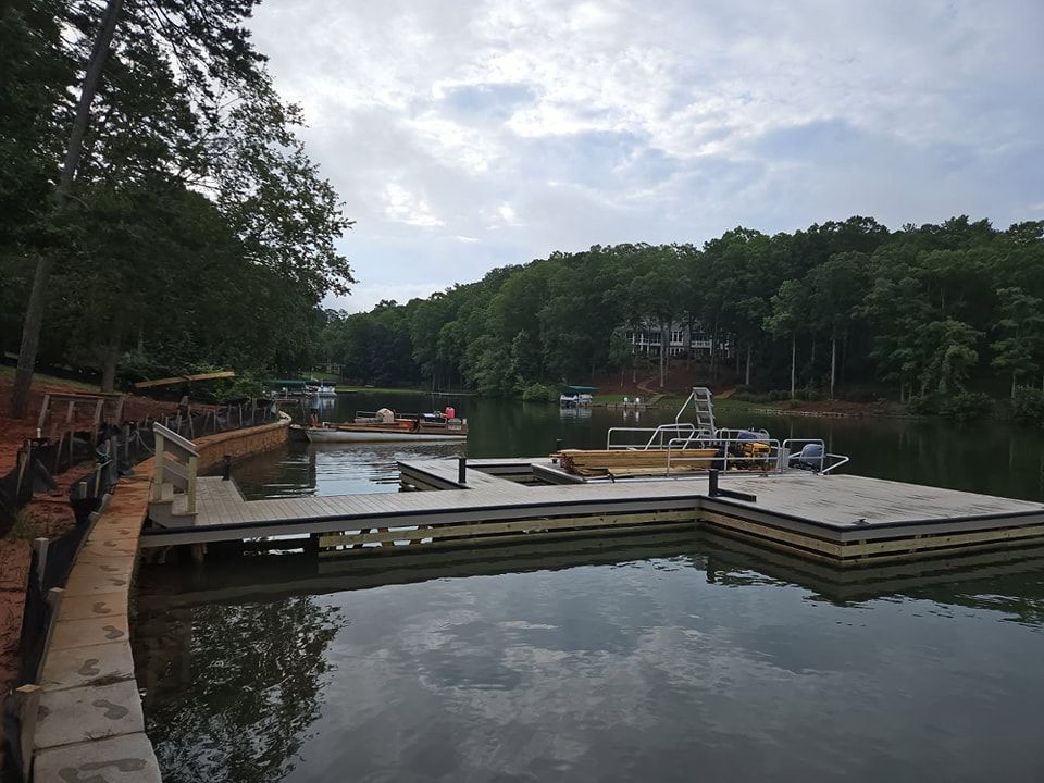 Wooden dock extends into a calm lake, surrounded by trees and overcast sky.