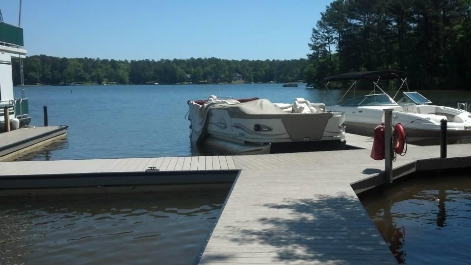 Dock on a lake with boats, clear blue sky, and treeline in the background.