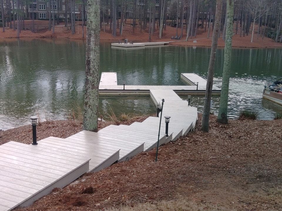 Wooden dock with stairs leading down to a lake, flanked by trees.