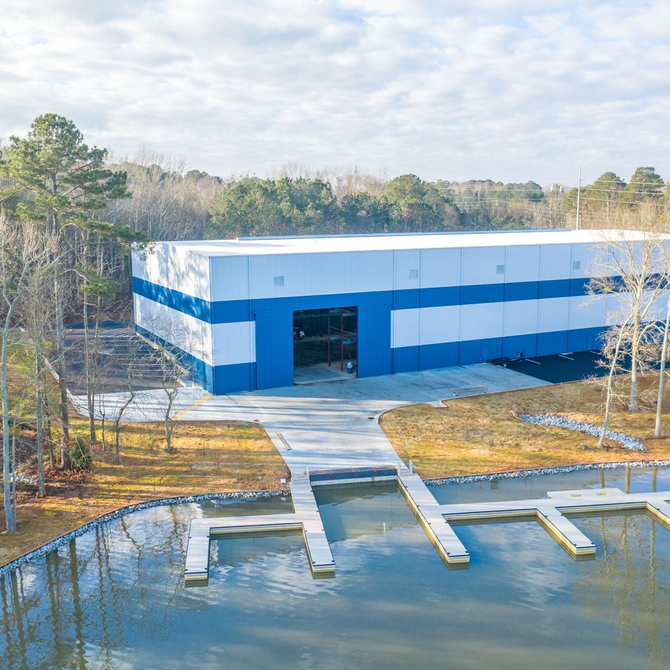 Blue and white boat storage building next to a lake with docks.