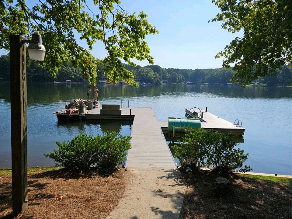 Two docks extending into a lake, surrounded by trees under a blue sky.