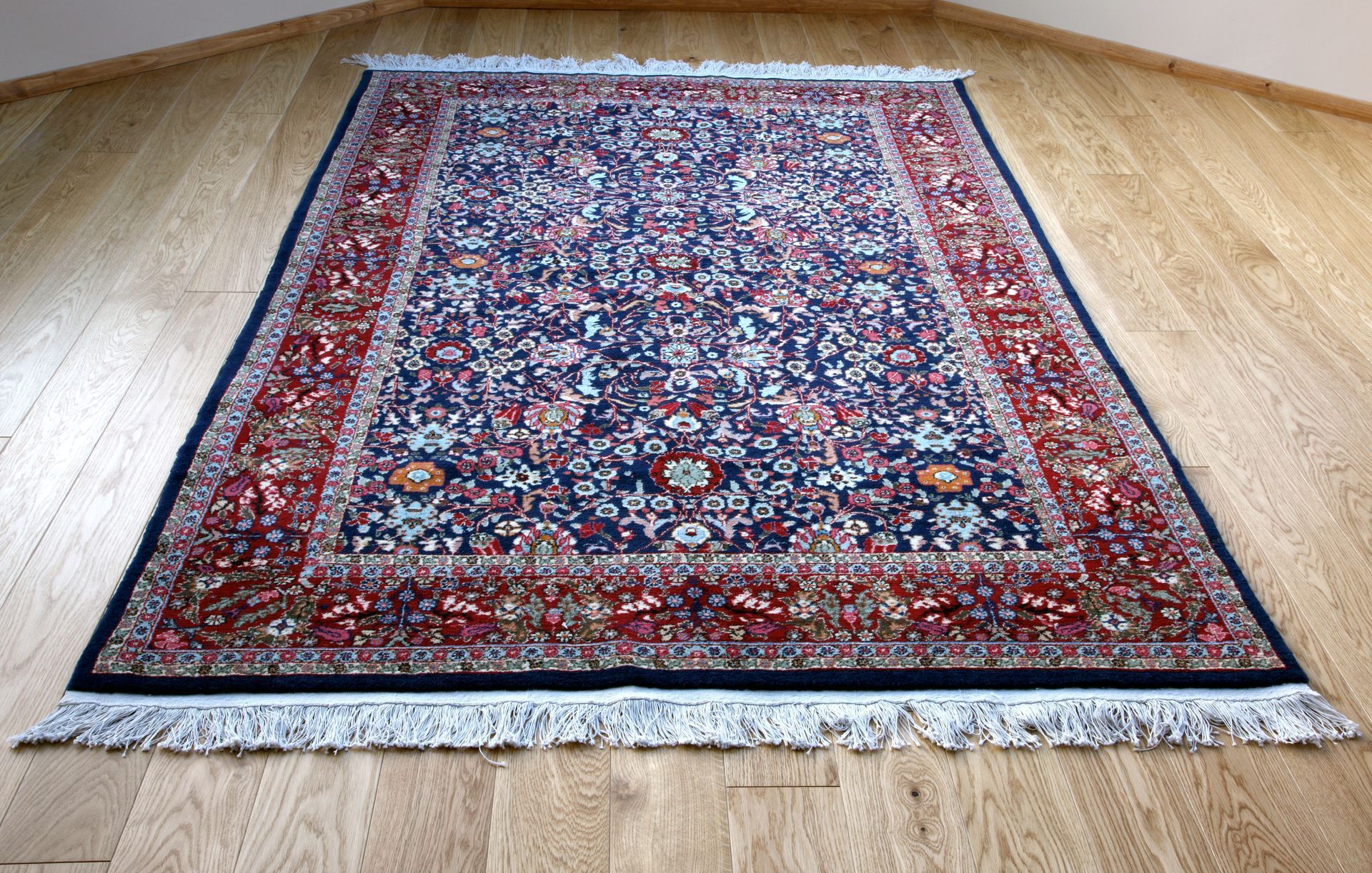 Red and blue patterned rug on a light wood floor, viewed from above.