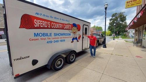 Sherock's mobile showroom trailer parked on a sidewalk, with a man walking beside it.