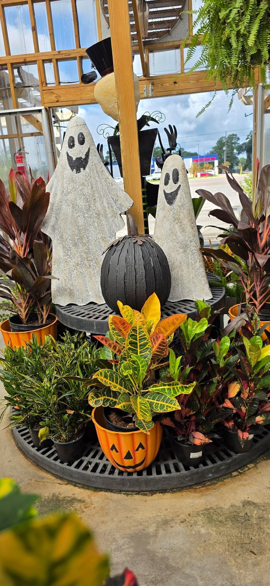 Decorative penguin sculpture in a planter, surrounded by colorful tropical plants outdoors