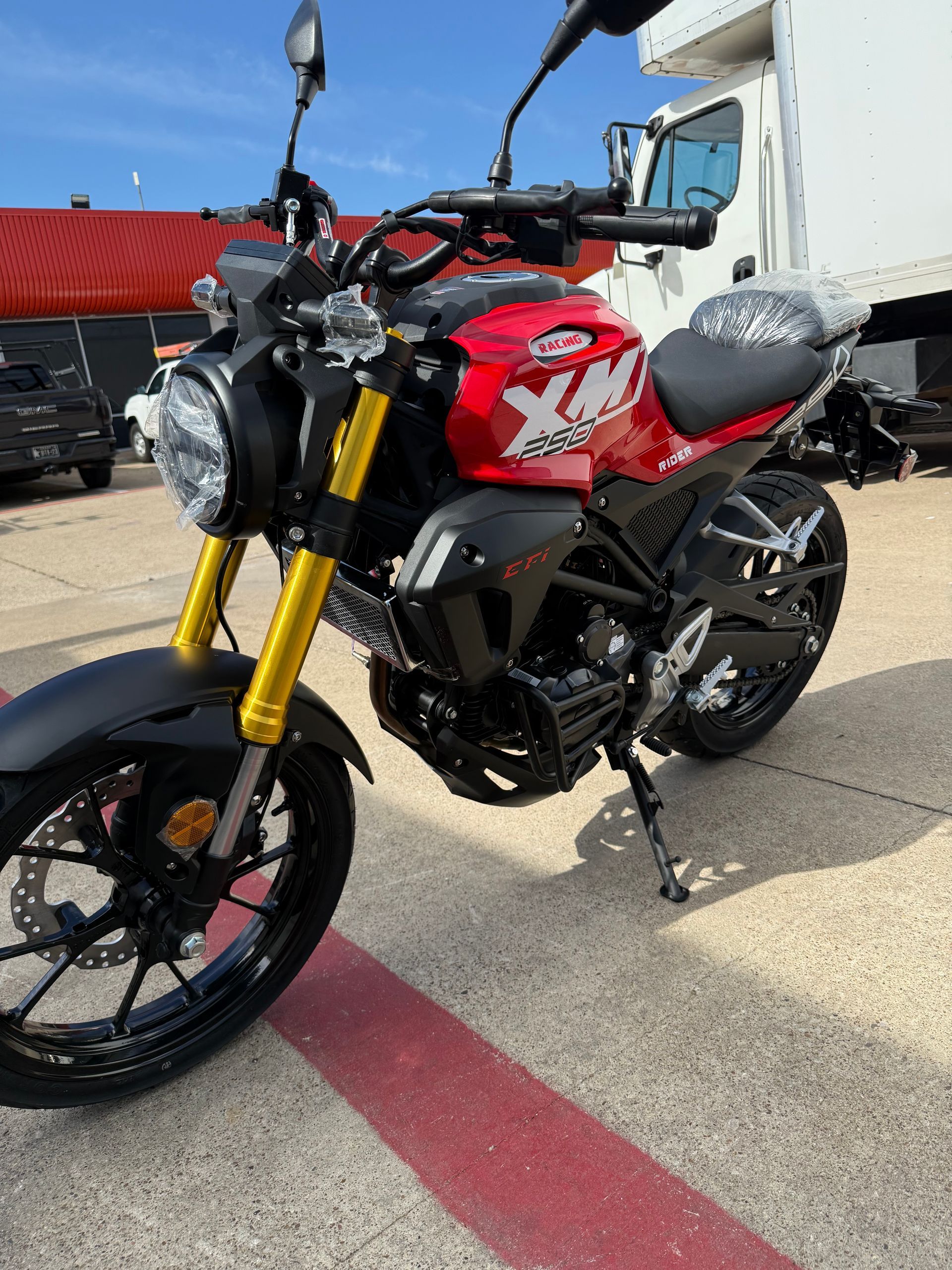 Black and red sport motorcycle parked on pavement outside a building under bright daylight