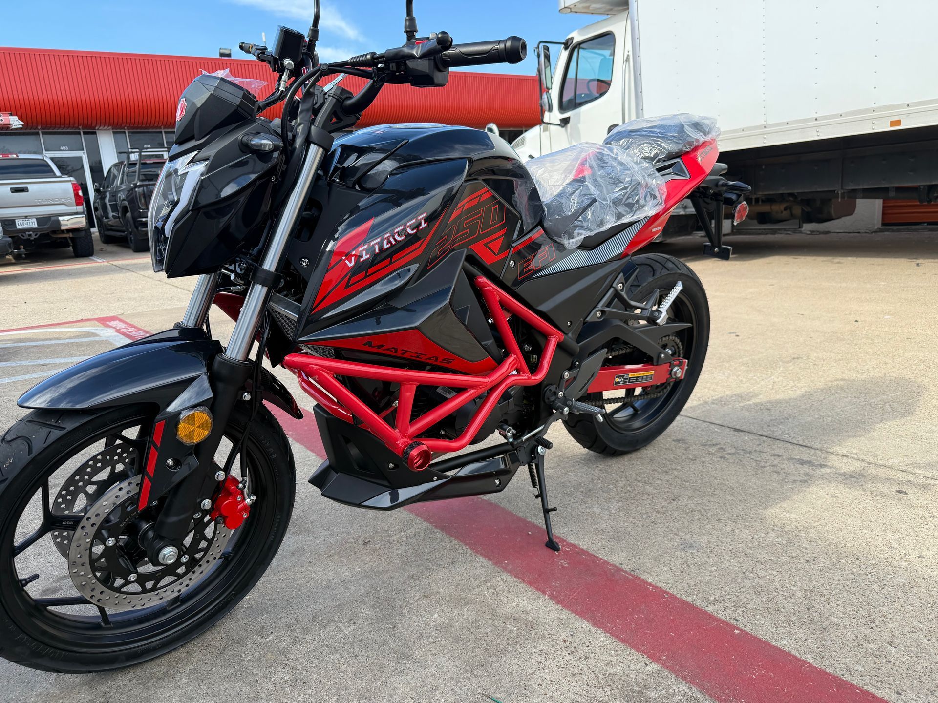 Black and red sport motorcycle with a red frame parked outdoors on pavement
