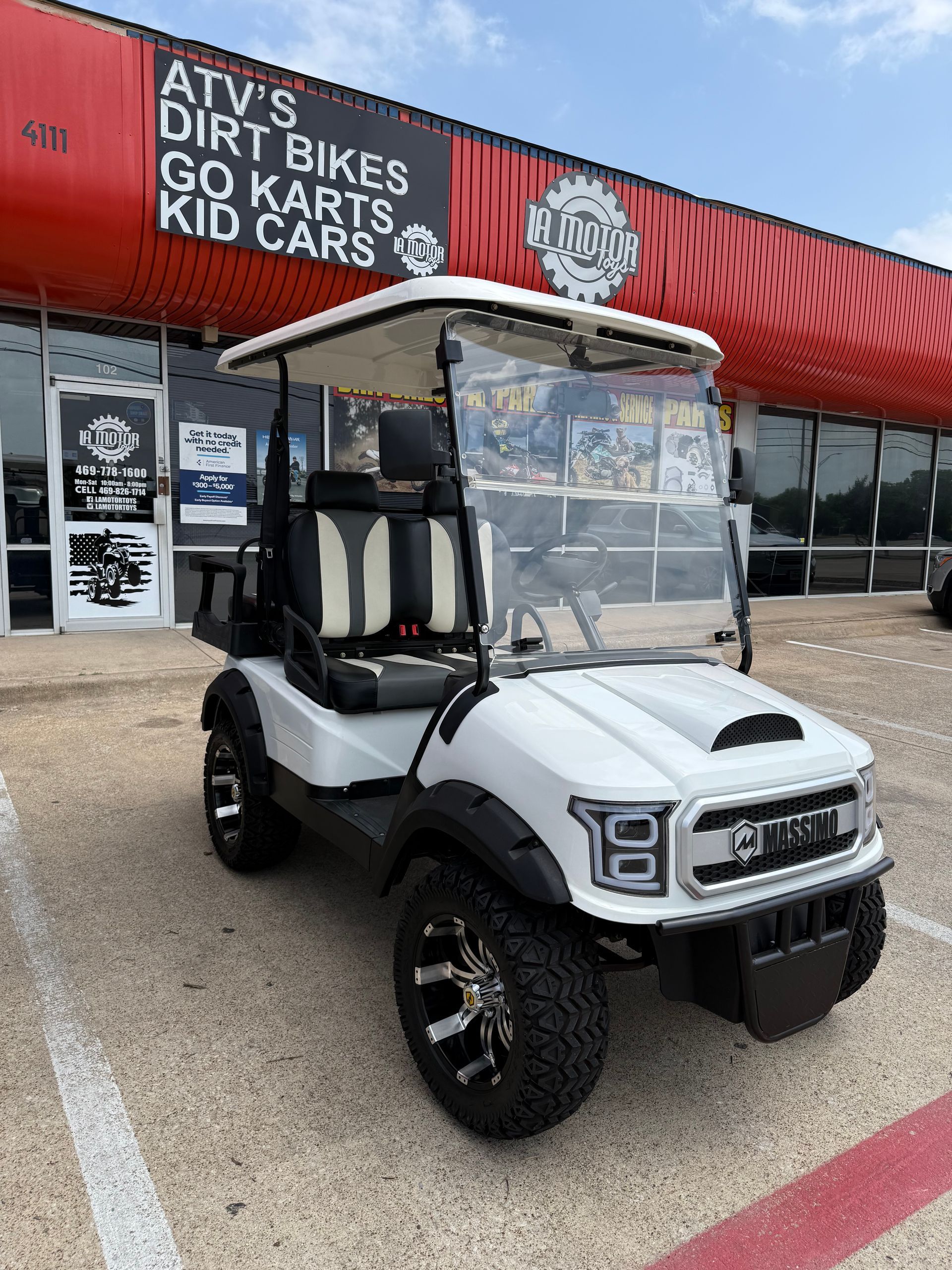 White golf cart parked outside ATV’s Dirt Bikes Go Karts Kid Cars shop