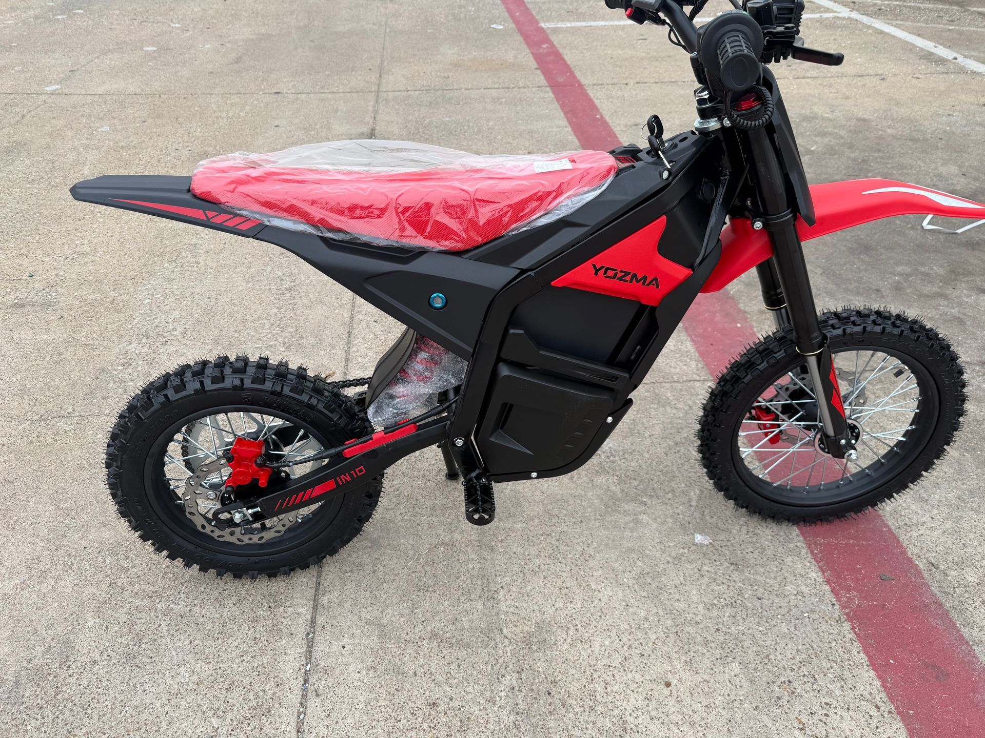 Red and black dirt bike parked on a concrete surface