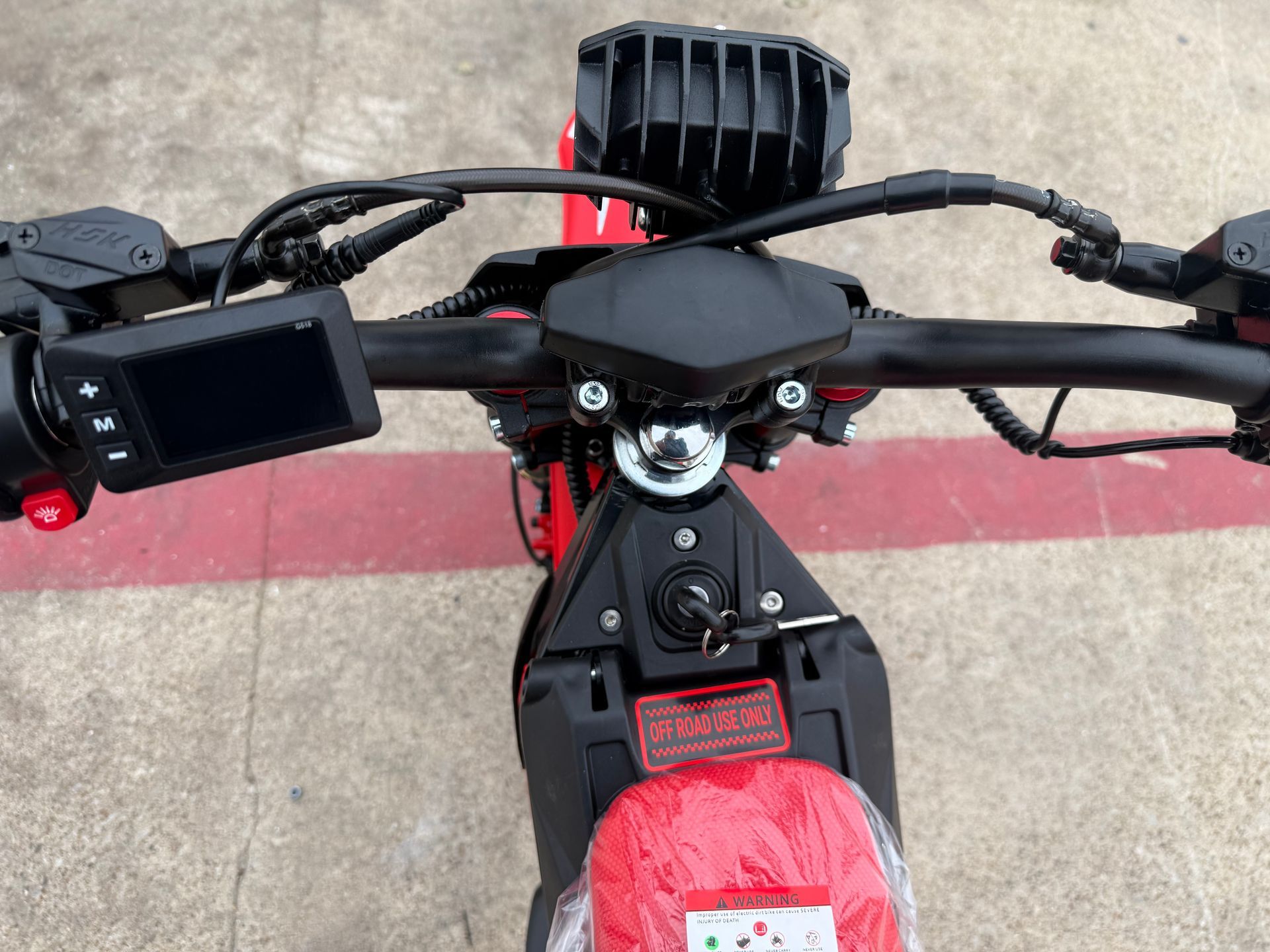 Handlebars and controls of a black-and-red electric scooter viewed from above.