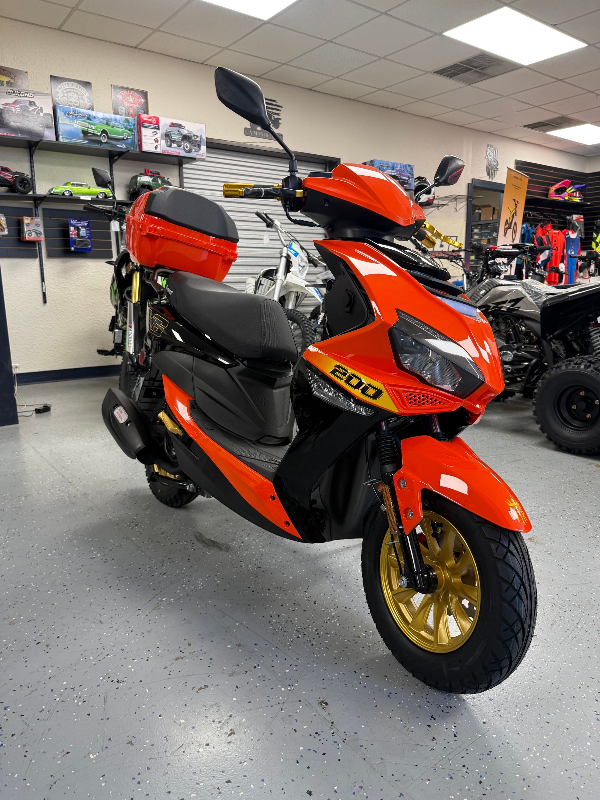 Orange and black three-wheeled scooter on display in a showroom with shelves in the background