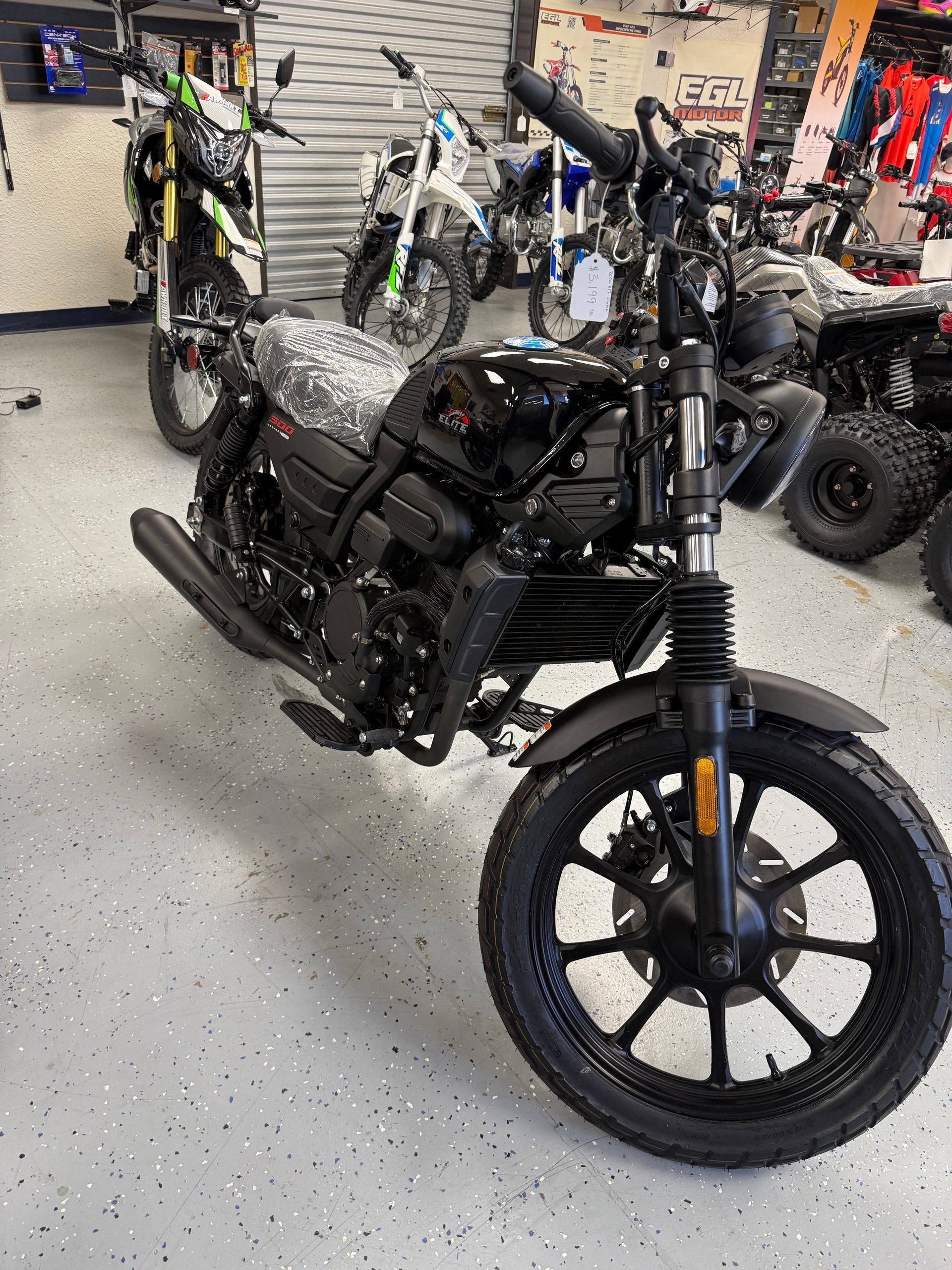 Black electric-style motorcycle displayed indoors among other bikes.