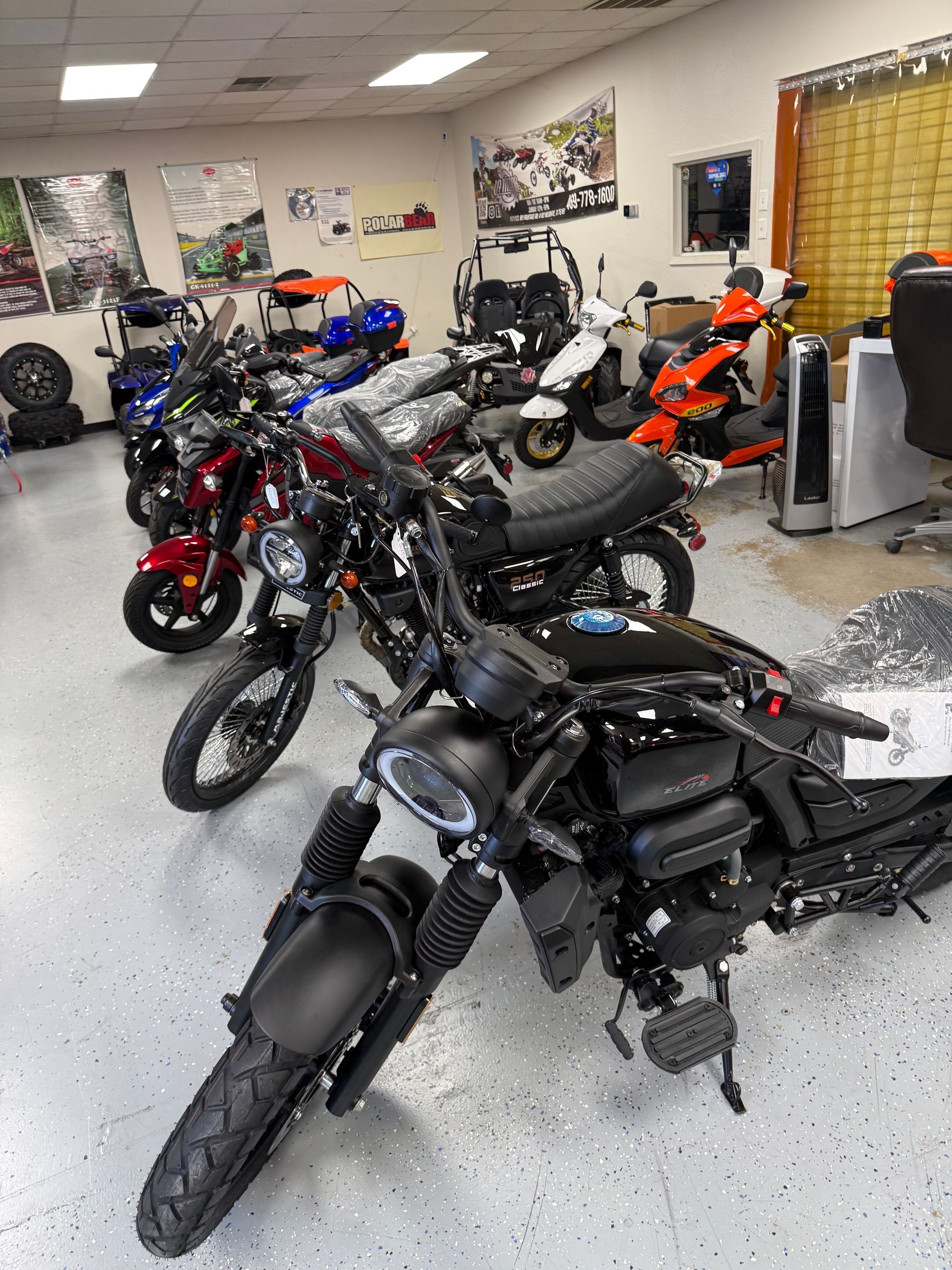 Row of parked motorcycles in a showroom or garage, including black, red, and orange bikes.