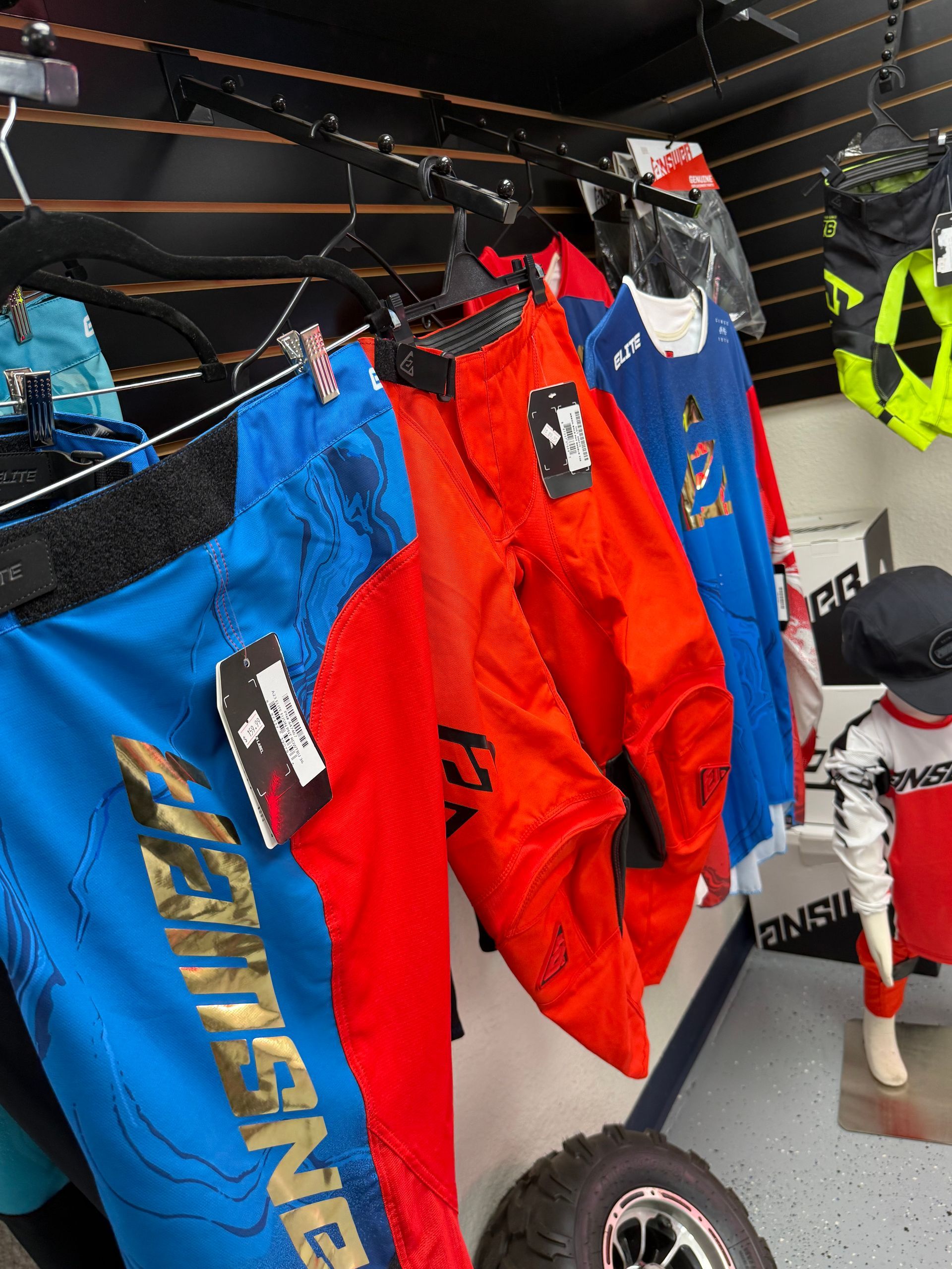 Bright motocross jerseys and gear hanging on display racks in a shop