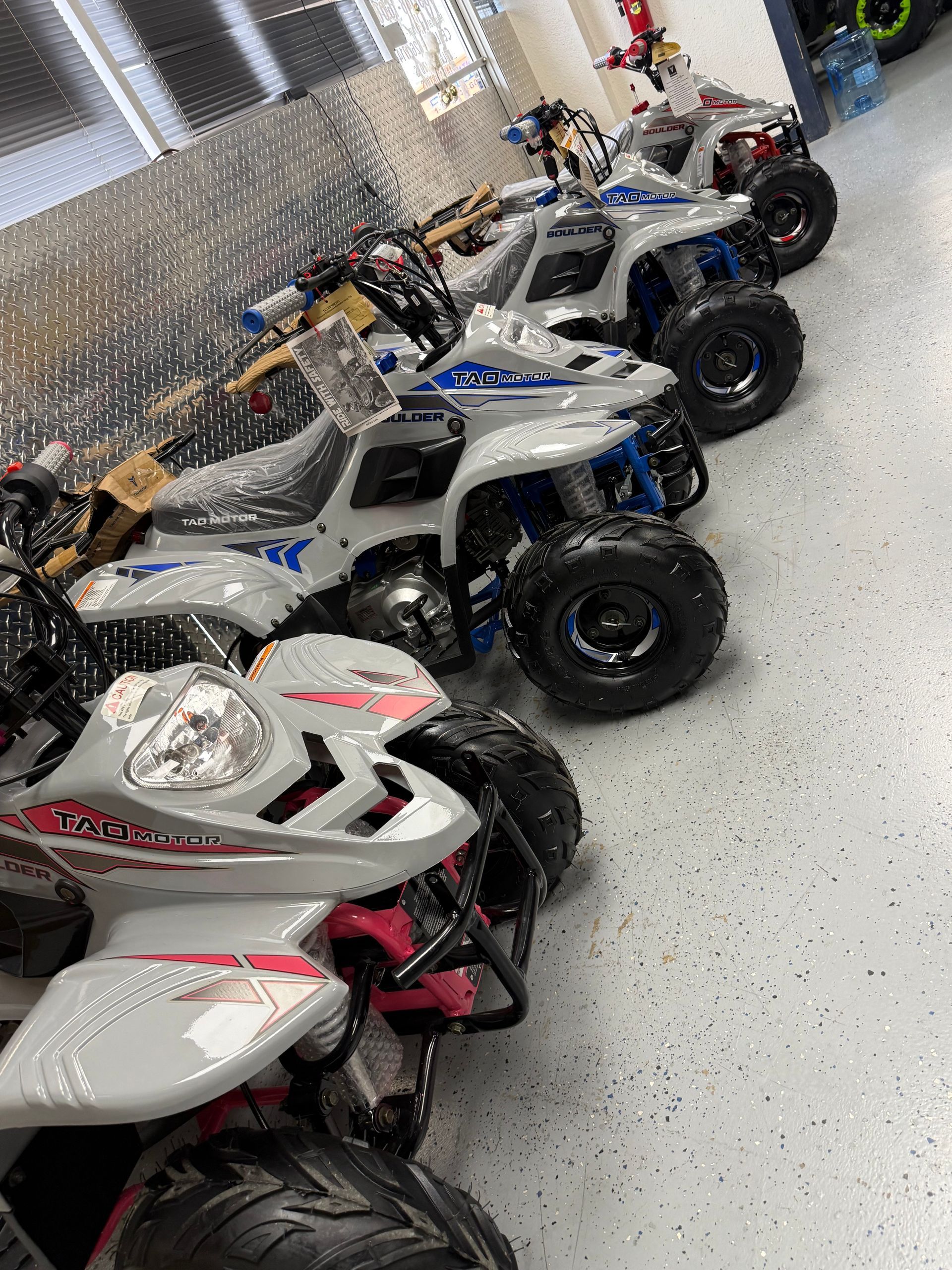 Row of white and blue all-terrain vehicles parked indoors on a showroom floor
