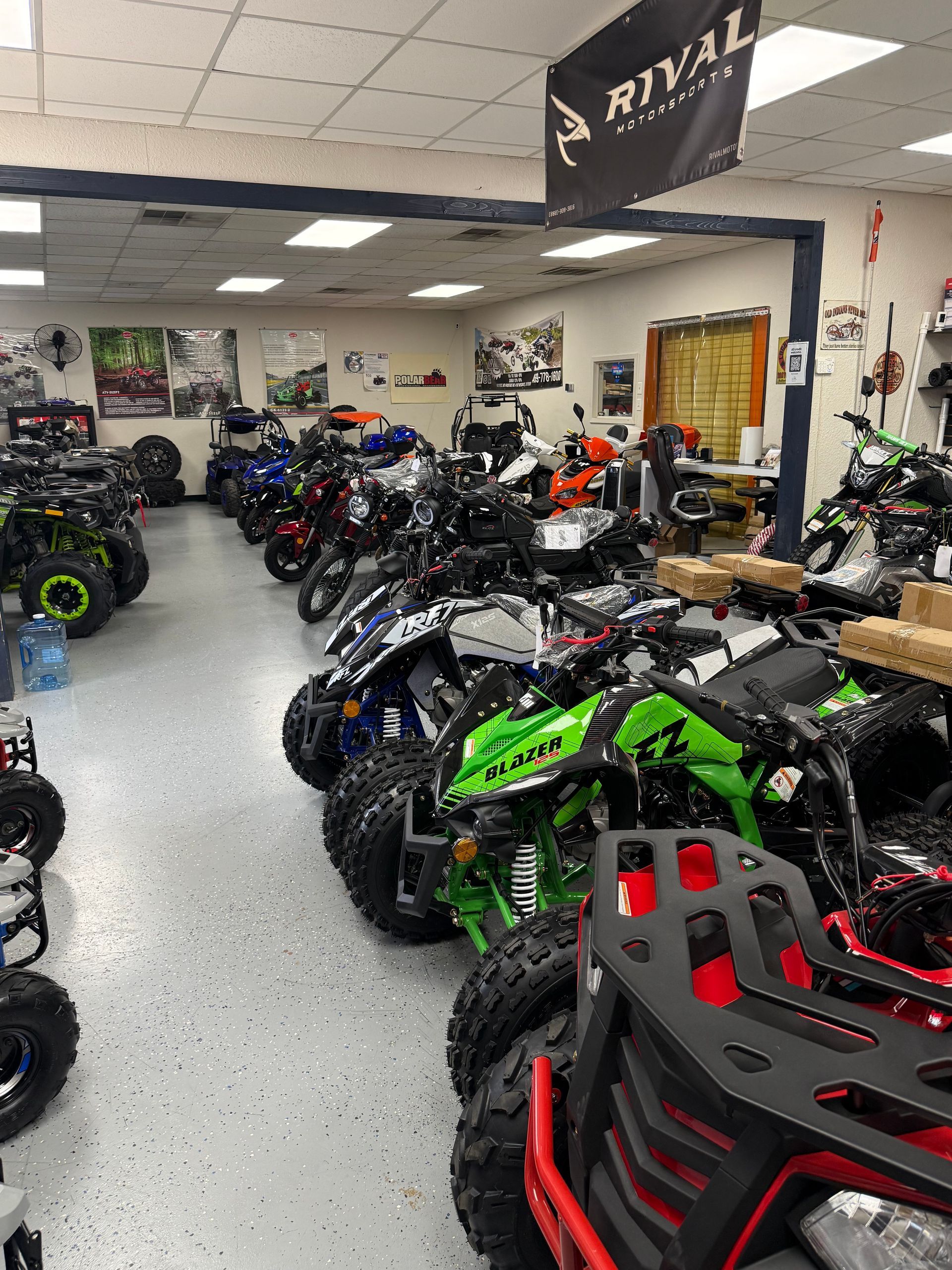 ATV showroom with rows of off-road vehicles, including green and red models, in a bright indoor space