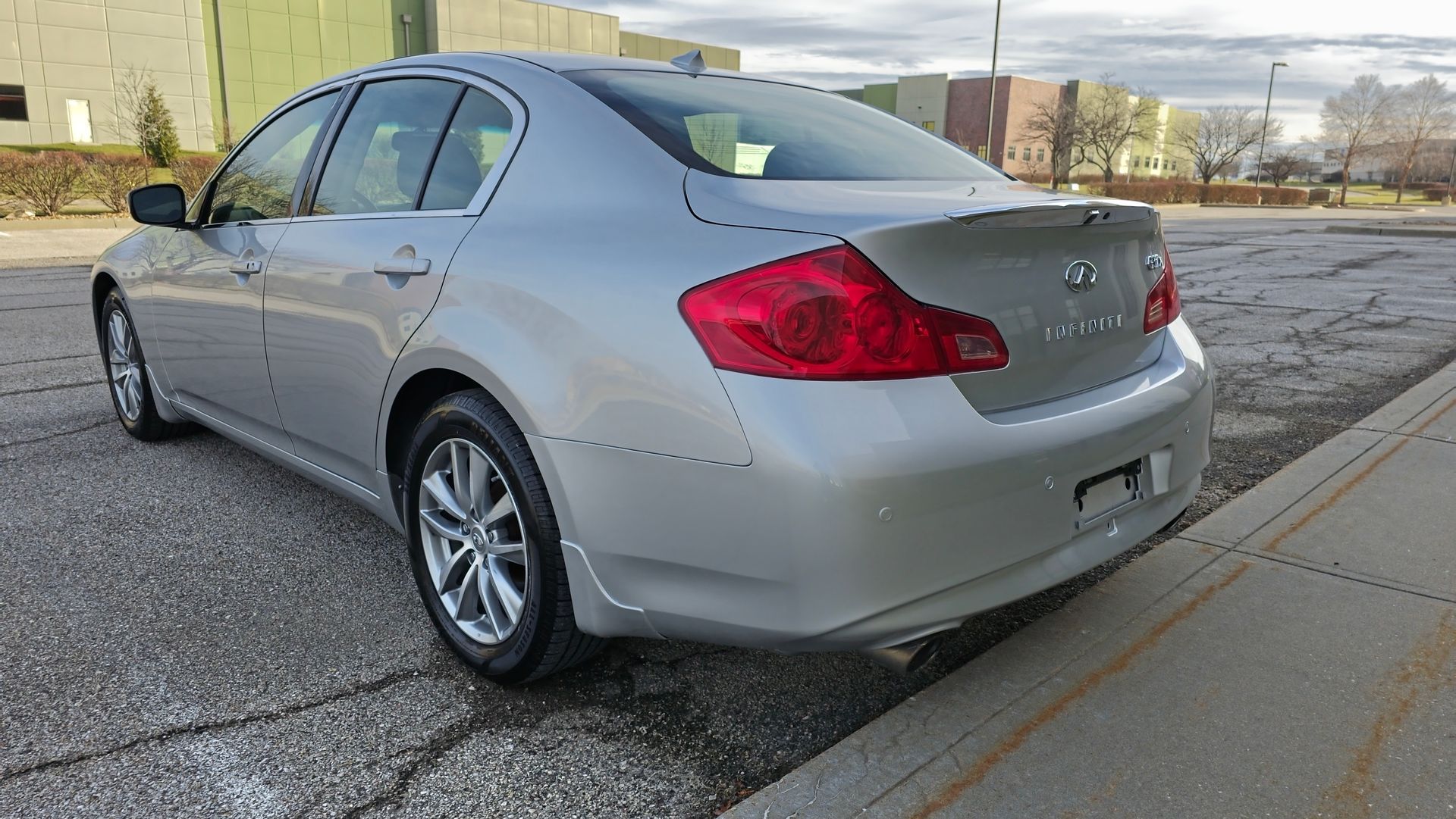 Silver sedan car parked on asphalt, near a building.