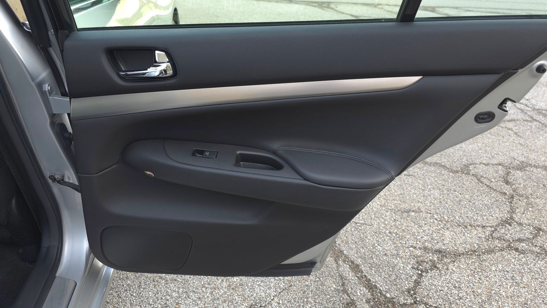 Car's interior: black door panel, silver trim, window controls, and handle.