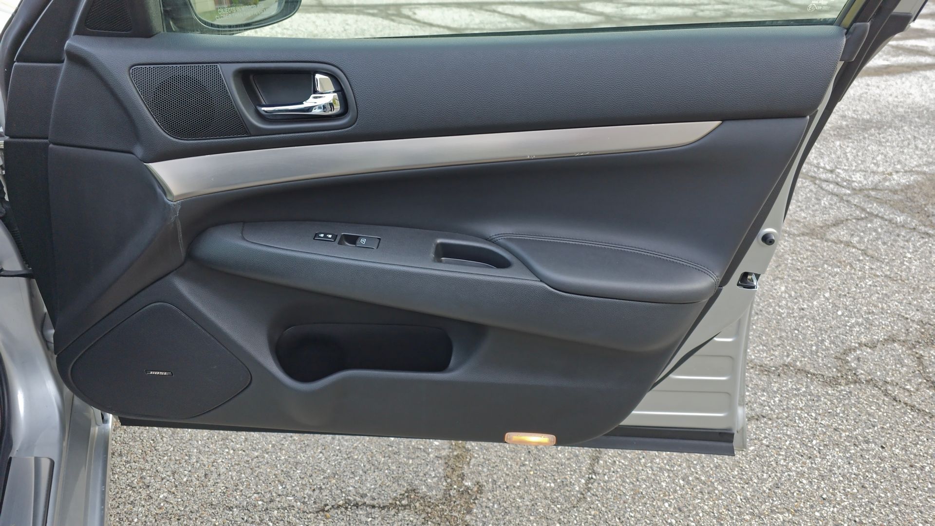 Car door interior, black and gray panel with controls and speaker.