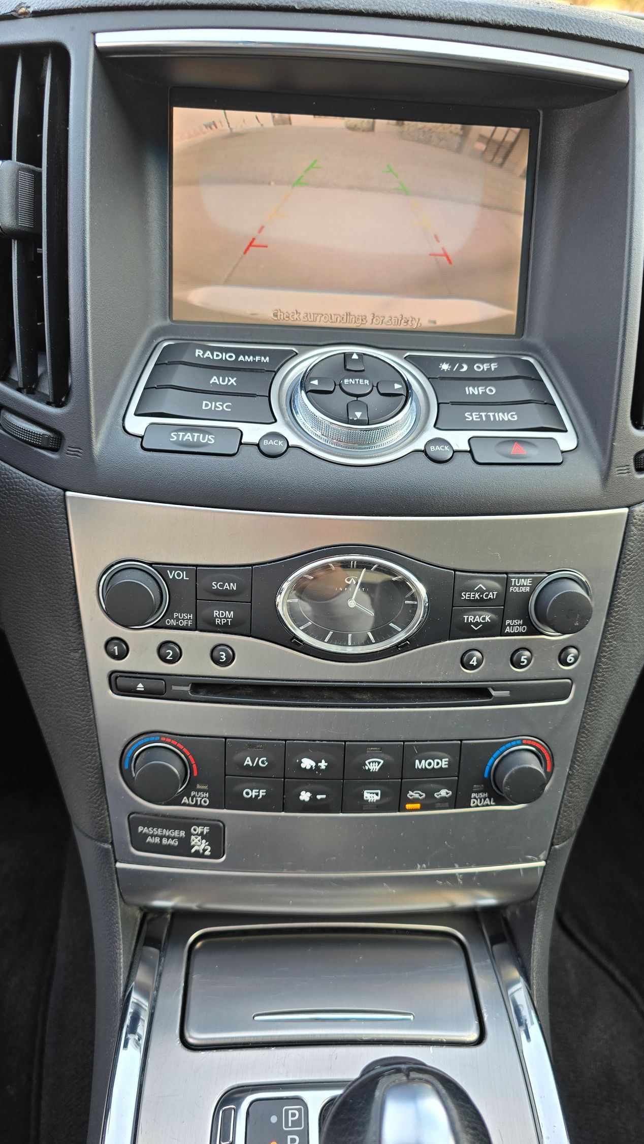 Car dashboard featuring a central display screen, buttons, dials, and a gear shift. Silver and black.