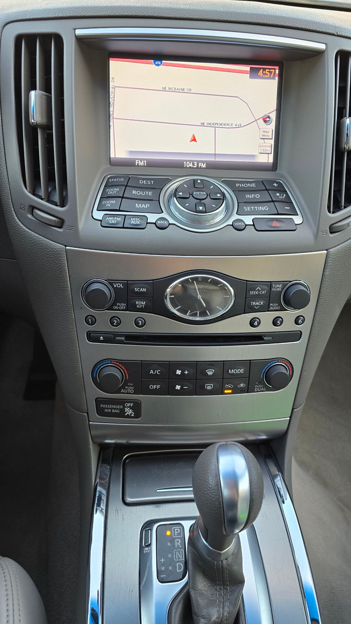 Car interior showing navigation screen, dashboard controls, and gear shift.