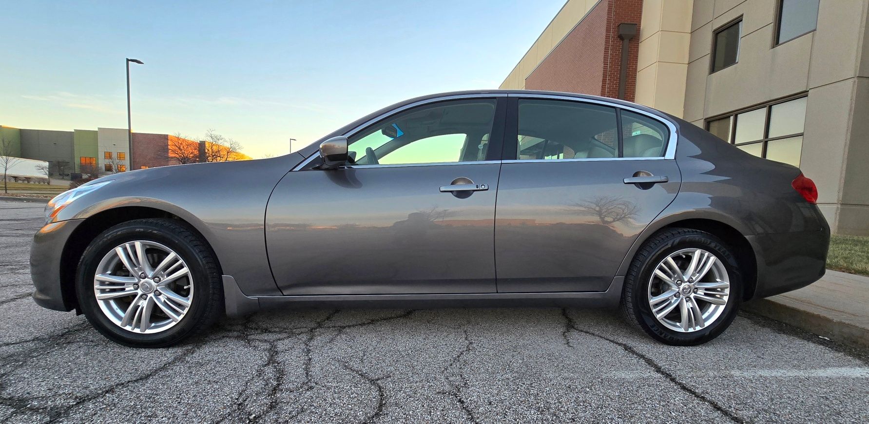 Gray Infiniti sedan parked on asphalt in front of a building.