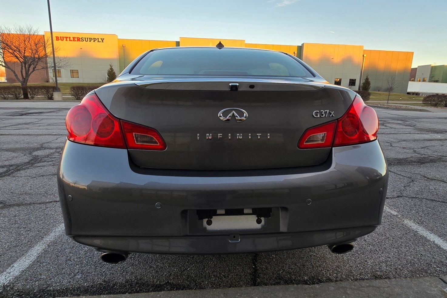 Rear view of a dark gray Infiniti G37 coupe parked in a parking lot.