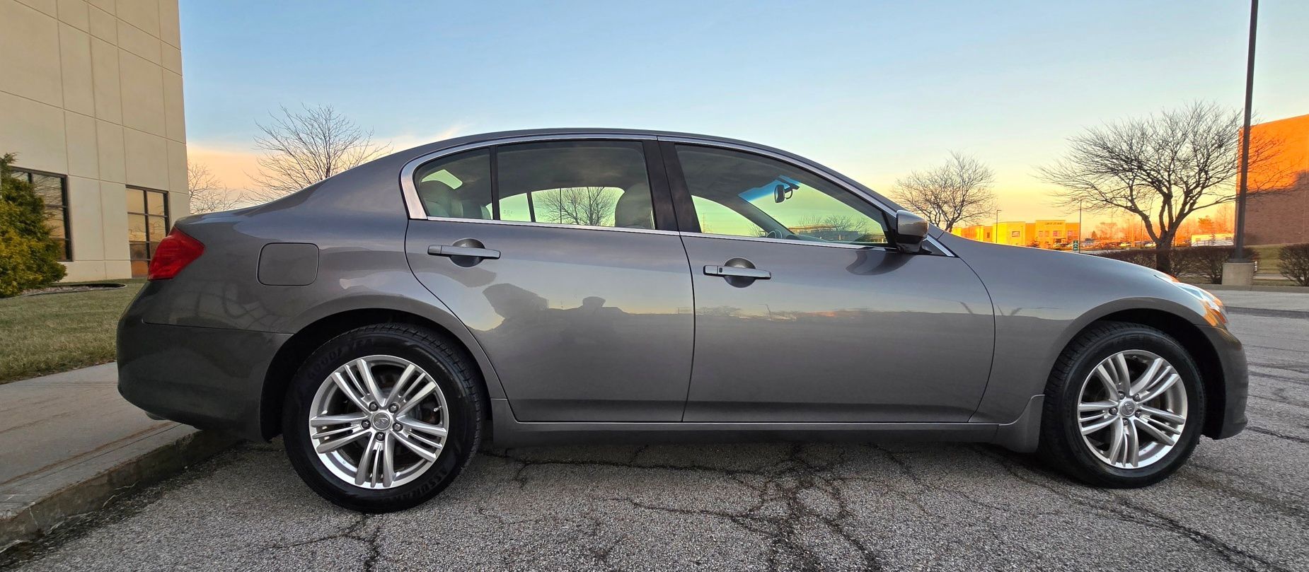 Gray Infiniti G37 sedan parked on asphalt next to a curb.