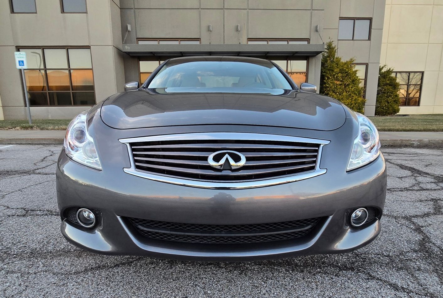Gray Infiniti G37 coupe parked in front of a building; front view showing grill, headlights, and Infiniti logo.