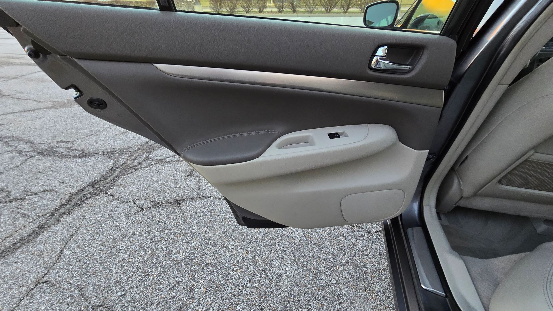 Car door interior, gray and tan, with window controls and silver trim.