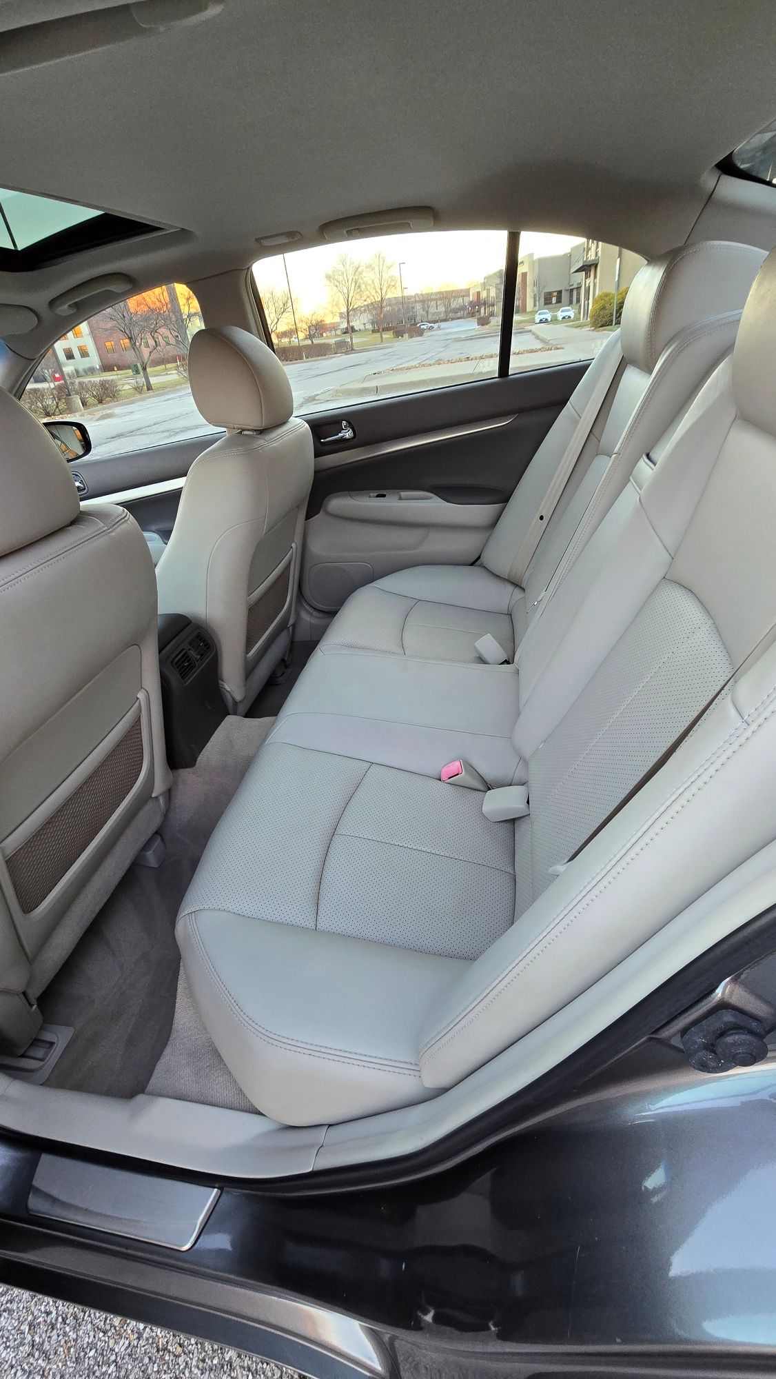 Gray car interior with cream leather seats, sunroof open, daylight.