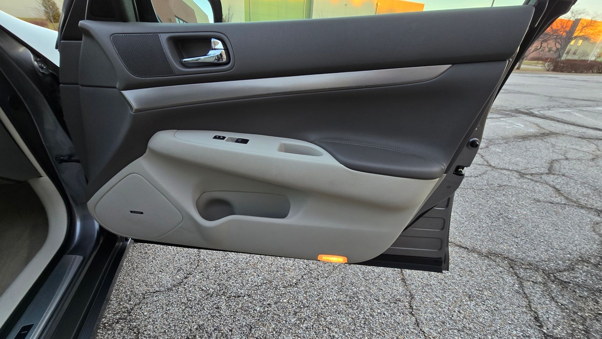 Car door interior with tan and black panels, a speaker, and a window control panel.