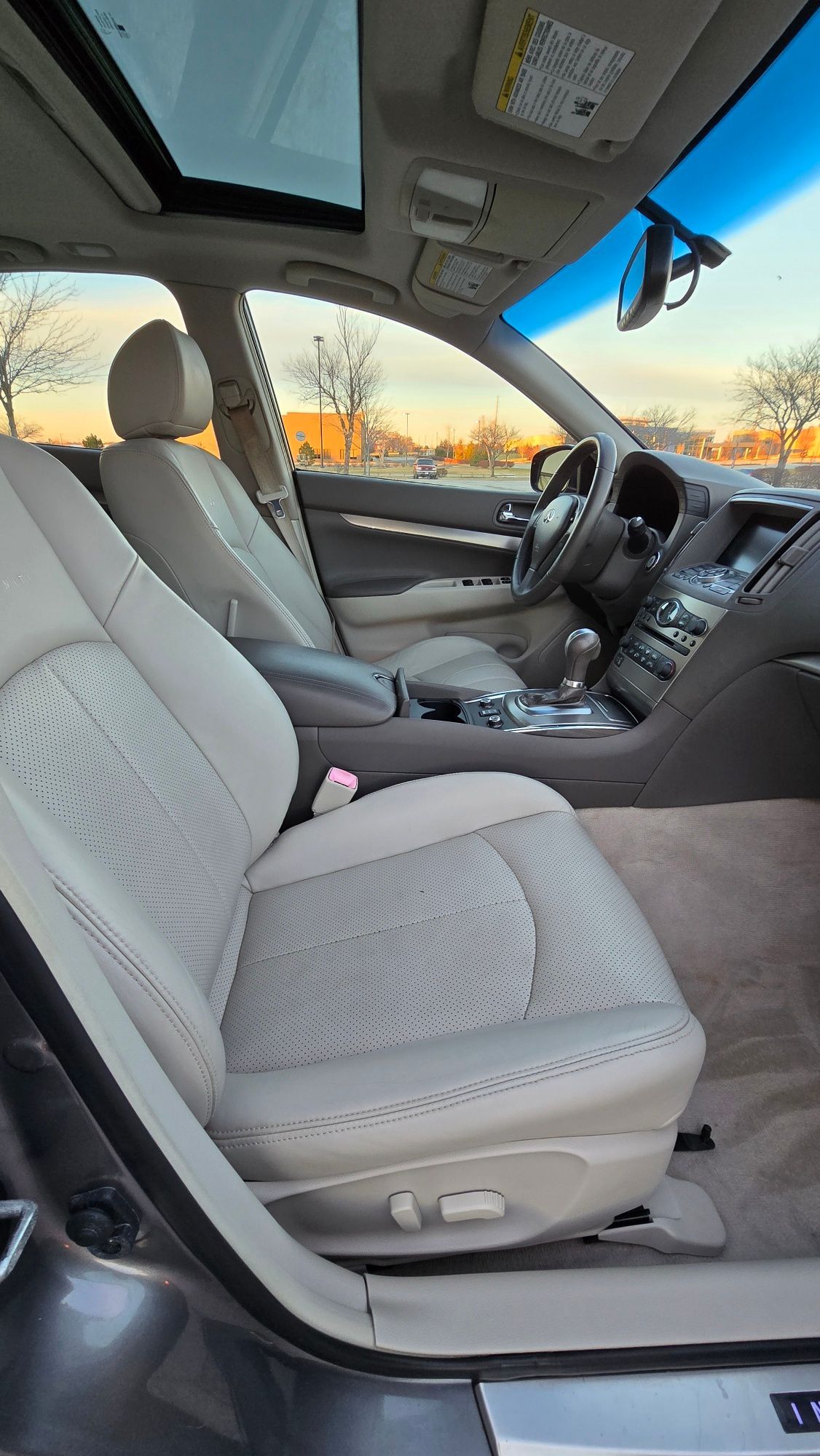 Interior of a car with beige leather seats and a sunroof, viewed from the driver's side.